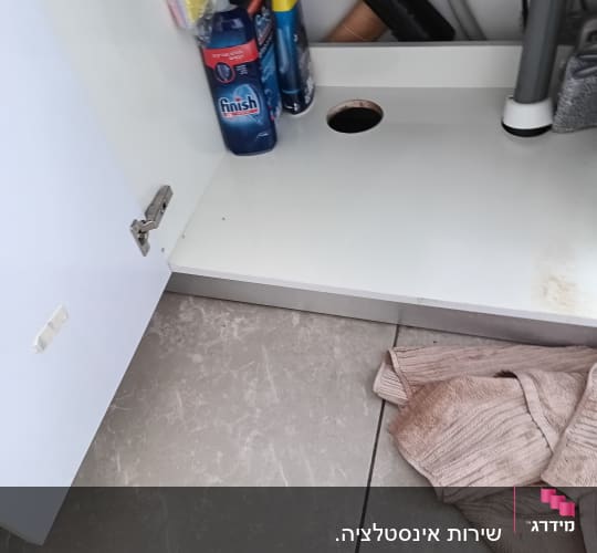 ארון פתוח עם מוצרי ניקוי וצינורות אינסטלציה